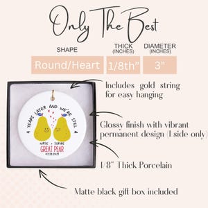 May include: A white ceramic ornament with a glossy finish, featuring two yellow pear illustrations and the text "4 years later and we're still a GREAT PEAR." Includes a gold string for hanging. The ornament is 3 inches in diameter and 1/8th inch thick, presented in a matte black gift box.