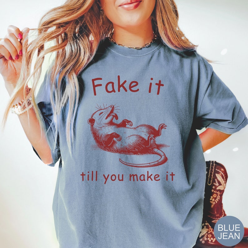 May include: A blue t-shirt with a red graphic of a possum and the text "Fake it till you make it".