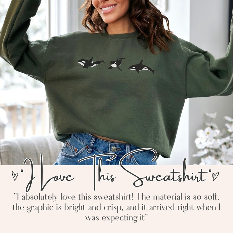 May include: A green sweatshirt featuring a graphic of three orcas swimming. The text "I love this sweatshirt" is written below the graphic.