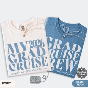 May include: Two folded t-shirts, one ivory and one blue jean, with the text "MY 2026 GRAD CRUISE CREW" and "GRAD CRUISE CREW" printed in blue. Each shirt has a necklace and the words "Sophie's Graduation" and "Graduation" printed on them.