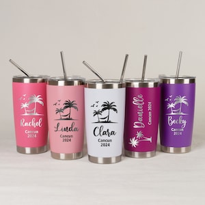 Op de afbeelding: Vijf gepersonaliseerde bekers in roze, wit en paars, elk met een zilveren deksel en rietje. De bekers hebben een tropisch ontwerp met palmbomen, een hangmat en de namen Rachel, Linda, Clara, Danielle en Becky, met "Cancun 2024".