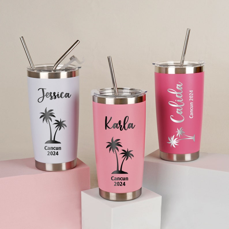 May include: Three stainless steel tumblers with lids and straws. One is white with "Jessica" and a palm tree graphic, another is pink with "Karla", and the third is pink with "Calida". All have "Cancun 2024" text.
