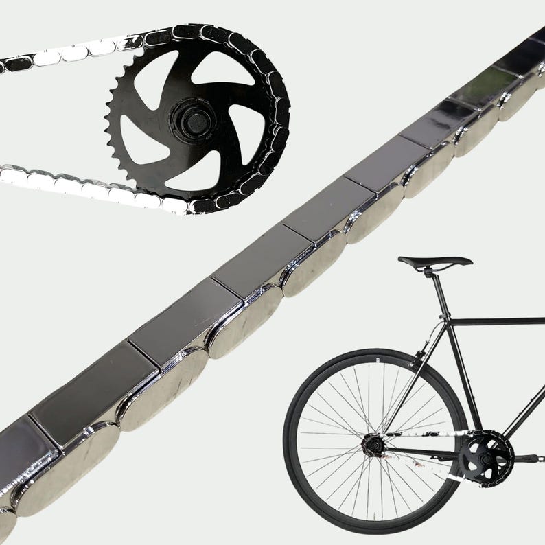 Puede incluir: Una cadena de bicicleta con un pi&ntilde;&oacute;n negro y una cadena negra y plateada. Una bicicleta negra est&aacute; en el fondo. La cadena est&aacute; hecha de eslabones rectangulares de color plateado.