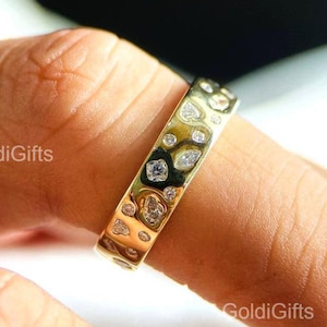 Könnte beinhalten: Ein goldfarbener Ring mit strukturierter Oberfläche und eingebetteten, klaren Edelsteinen. Der Ring hat ein einzigartiges Design mit unregelmäßigen Formen und wird am Finger getragen. Der Text "GoldiGifts" ist sichtbar.