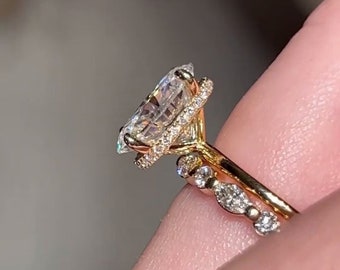 May include: A gold engagement ring with a large, clear, pear-shaped diamond as the centerpiece. The diamond is surrounded by a halo of smaller diamonds. A matching gold band with small diamonds is also visible.