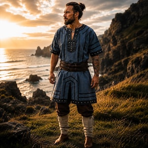 May include: A blue tunic with black trim and a brown belt. The tunic has short sleeves and is paired with brown shorts, tall socks, and brown boots. The outfit is worn outdoors with a scenic ocean and sunset background.