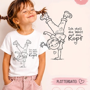 Op de afbeelding: Een wit t-shirt met een zwarte lijntekening van een kind dat een handstand doet, met de Duitse tekst Ich stell die Welt auf den Kopf en een klein hartje. Het ontwerp wordt ook apart getoond als digitaal bestand met de labels SVG, PNG en DXF.