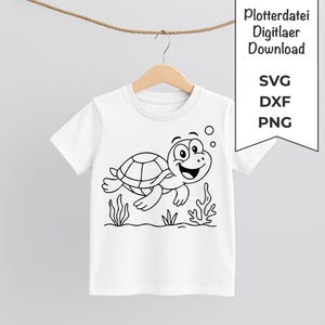 Könnte beinhalten: Weißes T-Shirt mit einem schwarz-weißen Cartoon-Schildkröten-Design. Die Schildkröte lächelt und schwimmt, mit Blasen und Seegras. Das T-Shirt hängt an einem Holzbügel.