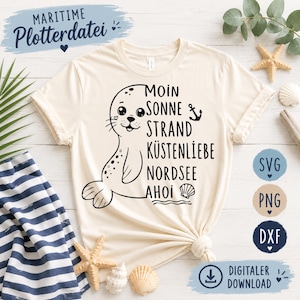 Könnte beinhalten: Cremefarbenes T-Shirt mit einem Cartoon-Robben-Design und dem Text "Moin Sonne Strand Küstenliebe Nordsee Ahoi" in Schwarz. Das Shirt hat auch ein blaues Banner mit dem Text "Maritime Plotterdatei".