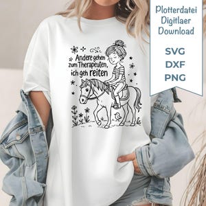 Op de afbeelding: Wit t-shirt met een zwart-witte afbeelding van een meisje op een paard, omringd door bloemen en sterren. De Duitse tekst luidt "Andere gehen zum Therapeuten, ich geh reiten." Inclusief "Plotterdatei Digitlaer Download" en bestandstype-opties.