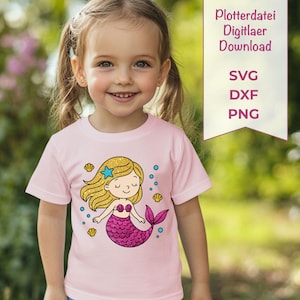 May include: A light pink t-shirt with a cartoon mermaid design. The mermaid has gold hair, a pink tail, and a blue starfish. The shirt also features blue bubbles and seashell graphics. A banner reads "Plotterdatei Digitlaer Download" with SVG, DXF, and PNG text.