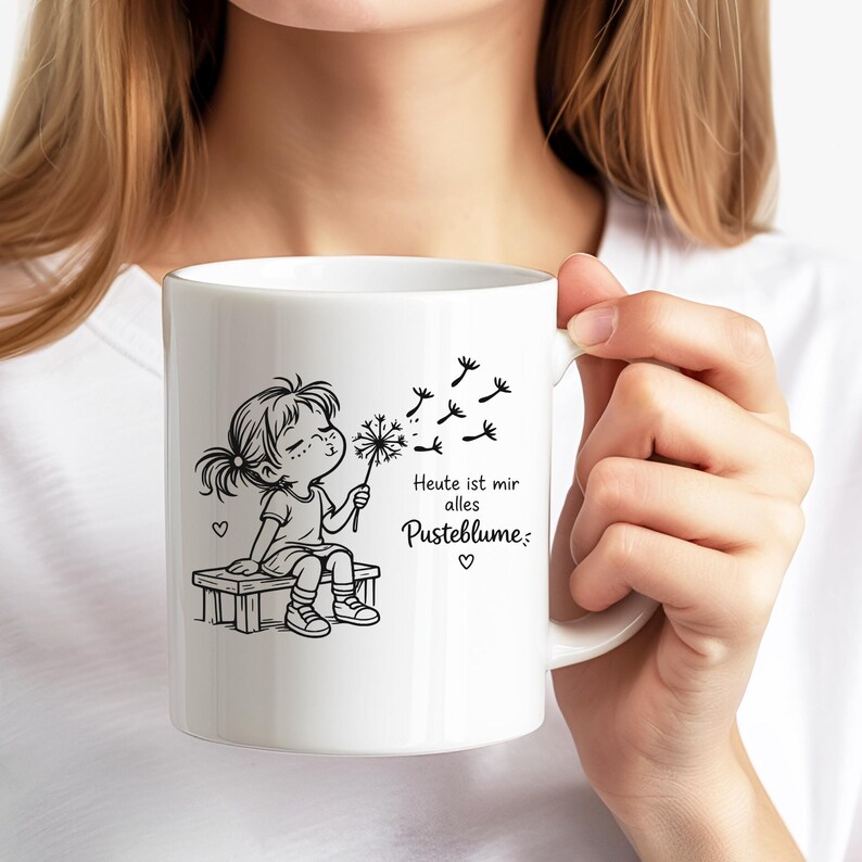 Puede incluir: Una taza de cer&aacute;mica blanca con una ilustraci&oacute;n de l&iacute;neas negras de un ni&ntilde;o sentado en un banco soplando un diente de le&oacute;n. El texto "Heute ist mir alles Pusteblume" est&aacute; impreso en negro junto a la ilustraci&oacute;n, junto a peque&ntilde;os corazones.