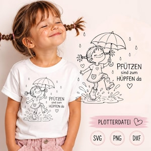 Può includere: Una t-shirt bianca con un disegno a linee nere di un bambino con le codine che tiene un ombrello e salta in una pozzanghera. Il testo recita PFÜTZEN sind zum HÜPFEN da. Il design include gocce di pioggia, cuori e le etichette di formato SVG, PNG e DXF.