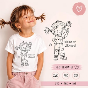 Puede incluir: Una camiseta blanca con un gráfico de líneas negras de una niña con coletas haciendo el signo de la paz y sacando la lengua. El texto dice Kleine Ulknudel. El diseño incluye pequeños corazones en los pantalones y junto al texto.