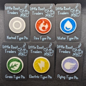 May include: Six enamel pins featuring different Pokemon types. The pins are round and have a white background with a colored icon in the center. The icons are: Normal (gray), Fire (orange), Water (blue), Grass (green), Electric (yellow), and Flying (purple). Each pin is labeled with the type name and the words "Little Root Traders".