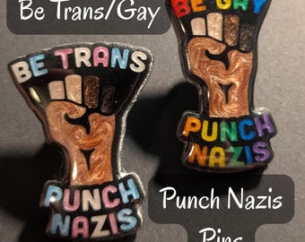 Pins de 1.5" con la frase "Sé trans/gay y golpea a los nazis"