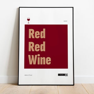 Puede incluir: Un póster enmarcado con fondo rojo y el texto "Red Red Wine" en color marrón claro. El póster también incluye un pequeño icono de una copa de vino y el texto "Labour of Love" en la parte inferior.