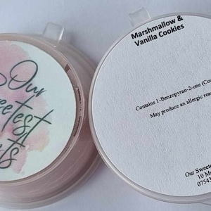 May include: A white jar with a pink and white label that says "Our Sweetest Scents". The jar is labelled with the scent "Marshmallow & Vanilla Cookies". The label also includes an allergy warning: "Contains 1-Benzopyran-2-one (Coumarin). May produce an allergic reaction."