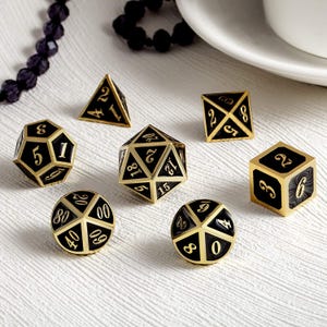 May include: A set of seven polyhedral dice in gold and black. The dice include a tetrahedron, cube, octahedron, dodecahedron, and icosahedron, along with two other dice. The numbers are in a contrasting gold color.