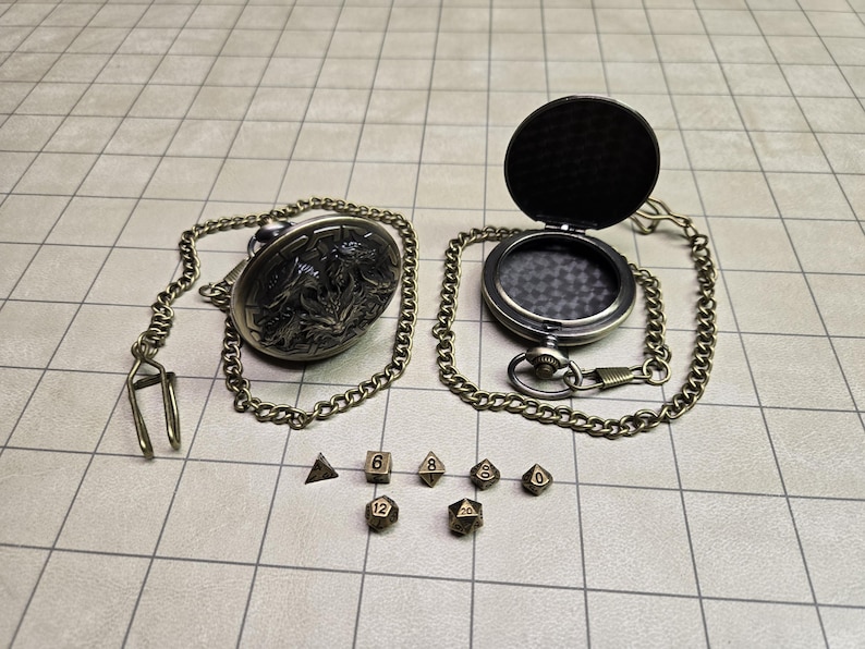 May include: An antique-style pocket watch with an open lid, chain, and a set of polyhedral dice. The watch has a detailed floral design on the back. The dice are in various shapes and sizes, perfect for tabletop gaming.