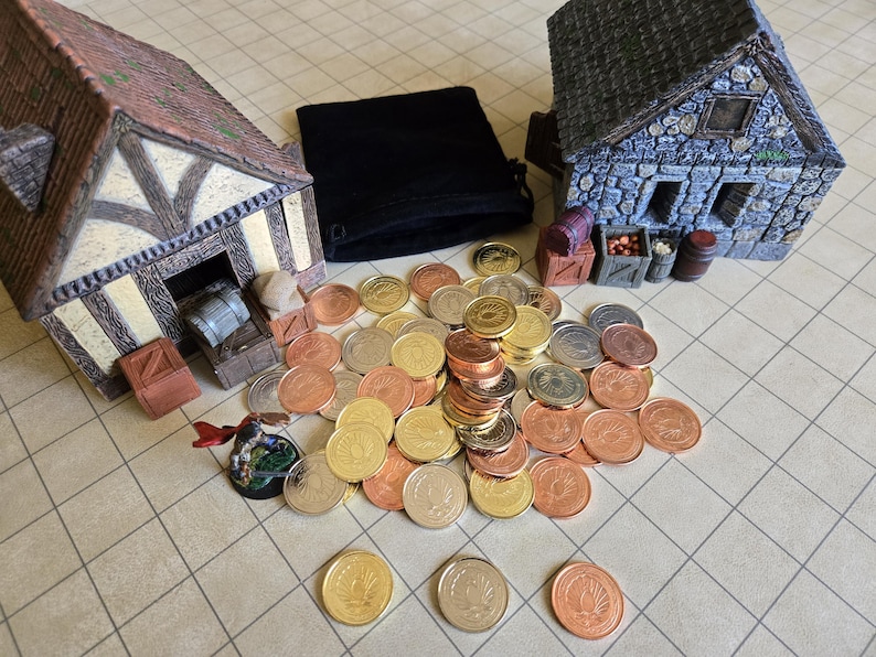 Puede incluir: Una escena de mesa con edificios en miniatura, una bolsa de terciopelo negro y una colecci&oacute;n de monedas doradas, plateadas y cobrizas. Los edificios tienen detalles arquitect&oacute;nicos y las monedas est&aacute;n dispersas.