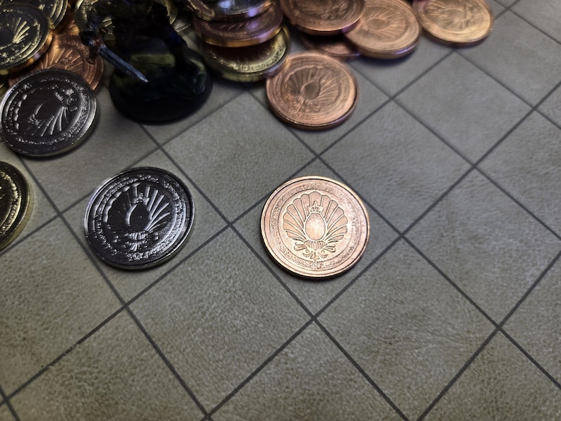 Puede incluir: Primer plano de varias monedas met&aacute;licas con dise&ntilde;os detallados, algunas plateadas y otras de color cobre. Las monedas est&aacute;n dispersas sobre una superficie gris con patr&oacute;n de cuadr&iacute;cula, con una figura en miniatura en el fondo.