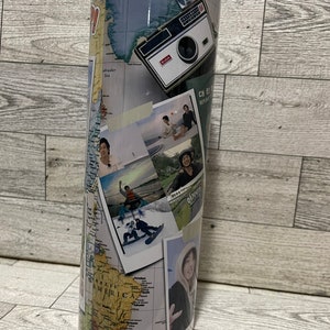 May include: A stainless steel travel tumbler with a collage of photos and a world map design. The photos include a vintage camera, a group of people on a beach, a person snowboarding, and a person standing in front of a mountain. The map shows South America, North America, and Greenland.
