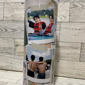 Könnte beinhalten: Ein weißer Reisebecher mit einem Weltkarten-Design. Der Becher zeigt zwei Fotos von zwei Personen in einem Boot, ein Foto von zwei Personen mit dem Rücken zur Kamera und ein Foto eines Gesichts. Der Becher hat einen durchsichtigen Deckel.