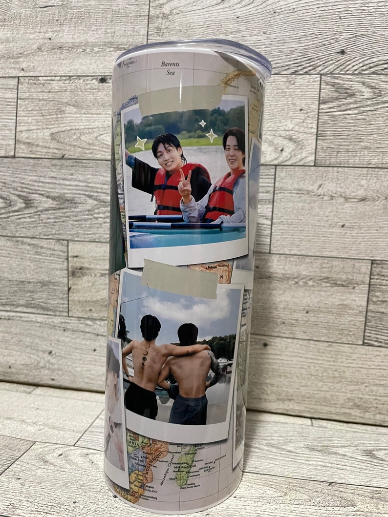 May include: A white travel tumbler with a world map design. The tumbler features two photos of two people in a boat, one photo of two people with their backs to the camera, and a photo of a person's face. The tumbler has a clear lid.