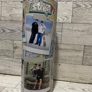 May include: A white travel mug with a collage of photos and a sticker that says "Are You Sure?" The photos show two people in different settings, including a snowy landscape and a forest.
