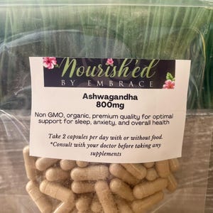 May include: A clear plastic bag filled with brown capsules labeled "Nourished by Embrace Ashwagandha 800mg". The label also states "Non GMO, organic, premium quality for optimal support for sleep, anxiety, and overall health. Take 2 capsules per day with or without food. *Consult with your doctor before taking any supplements."