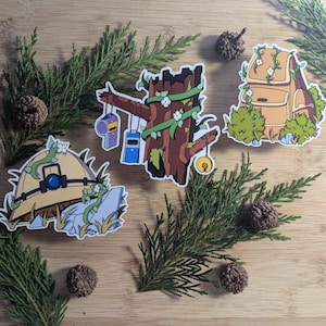 May include: Four illustrated stickers featuring a tree stump with vines, a backpack with vines, a hat with vines, and a rock with vines. The stickers are on a wooden surface with pine needles.