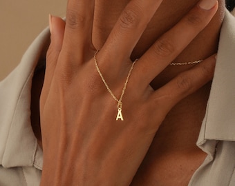 May include: A gold chain necklace with a small gold letter 'A' pendant.