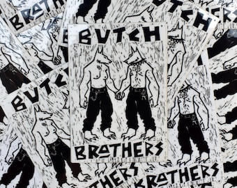 Könnte beinhalten: Ein rechteckiger Aufkleber mit einer schwarz-weißen Linolschnitt-Illustration von zwei anthropomorphen Wolfsfiguren, die Händchen halten. Die Figuren tragen dunkle Hosen und Gürtel. Der Text BUTCH BROTHERS ist in fetten Blockbuchstaben gedruckt.