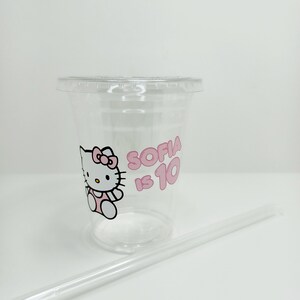 Puede incluir: Vaso de pl&aacute;stico transparente con un dise&ntilde;o de Hello Kitty rosa y el texto "Sofia tiene 10 a&ntilde;os". El vaso viene con una pajita de pl&aacute;stico transparente.