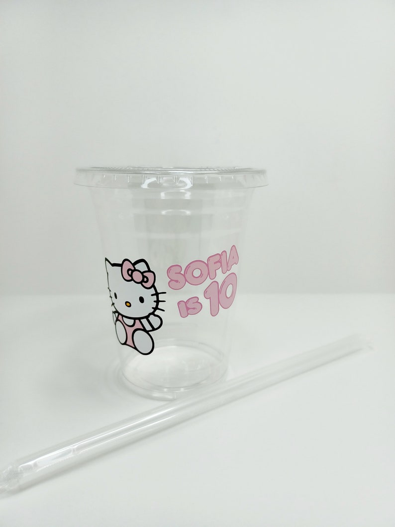 Puede incluir: Vaso de pl&aacute;stico transparente con un dise&ntilde;o de Hello Kitty rosa y el texto "Sofia tiene 10 a&ntilde;os". El vaso viene con una pajita de pl&aacute;stico transparente.