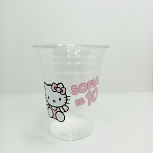 Puede incluir: Vaso de pl&aacute;stico transparente con un dise&ntilde;o rosa de Hello Kitty y el texto "Sofia tiene 10 a&ntilde;os".
