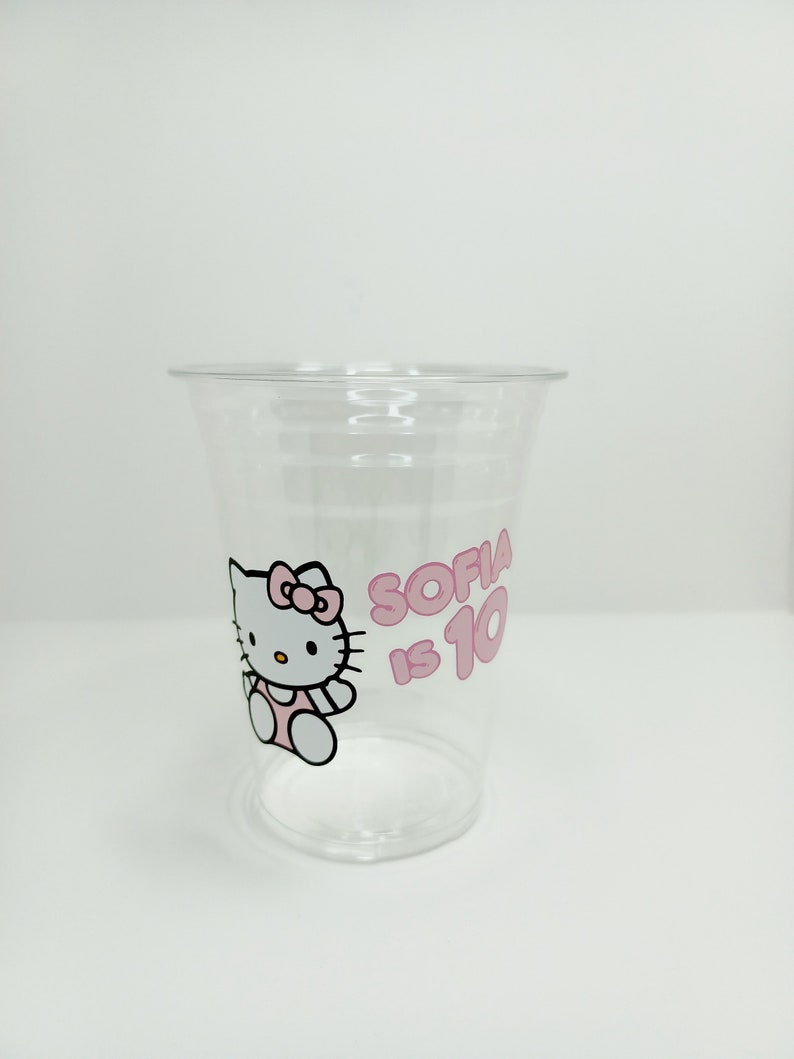 Puede incluir: Vaso de pl&aacute;stico transparente con un dise&ntilde;o rosa de Hello Kitty y el texto "Sofia tiene 10 a&ntilde;os".