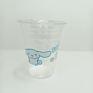 Puede incluir: Un vaso de pl&aacute;stico transparente con un perro de dibujos animados blanco y el texto "So is 1" en azul.