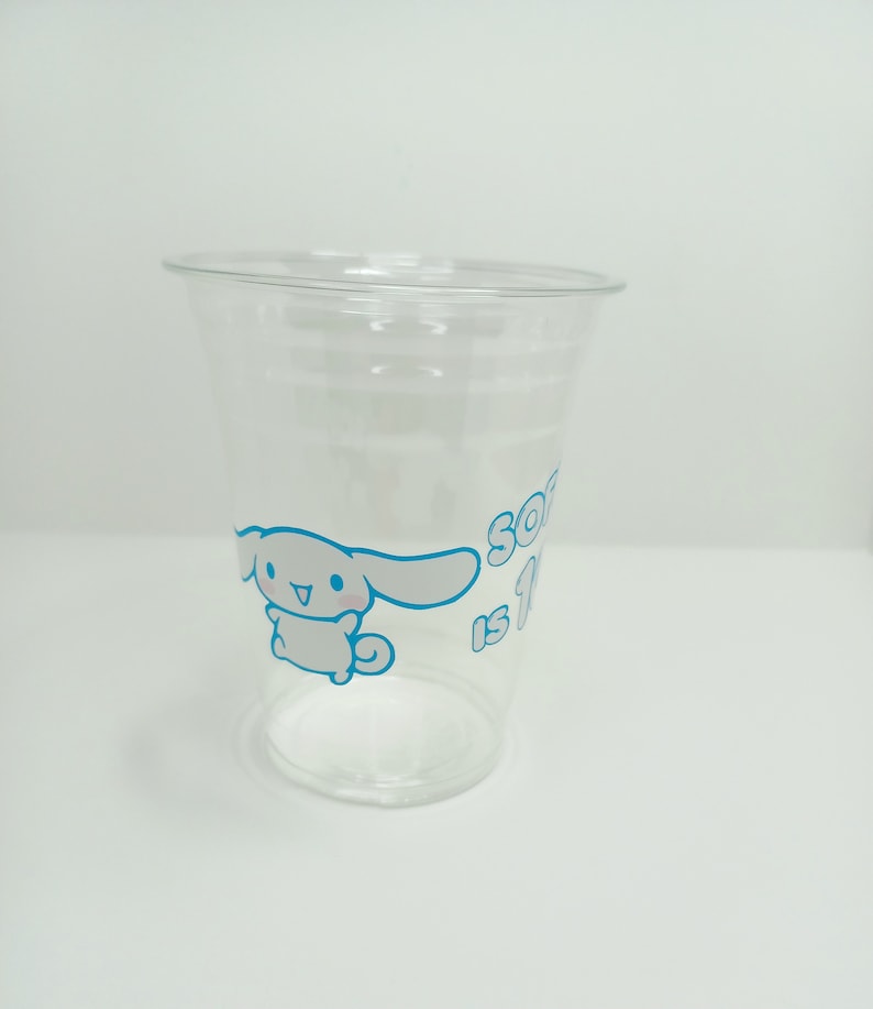 Puede incluir: Un vaso de pl&aacute;stico transparente con un perro de dibujos animados blanco y el texto "So is 1" en azul.
