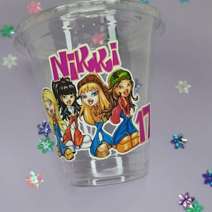May include: Clear plastic cup with a sticker featuring four cartoon girls with the text "Nikki" and the number "17".