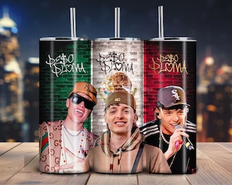 May include: A cylindrical metal tumbler with a straw featuring a graphic print of the Mexican flag and the text "PE$O PLOMA" in a graffiti style. The design includes three portraits of a person wearing hats and casual clothing against a brick wall.