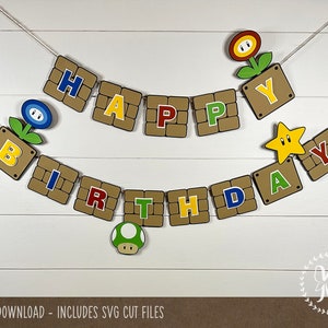 Könnte beinhalten: Ein braunes und beigefarbenes Banner mit den Worten "Happy Birthday" in bunten Buchstaben. Das Banner ist mit Bildern von Super Mario Bros.-Charakteren verziert, darunter ein Stern, ein Pilz und eine Blume.