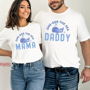 May include: White t-shirts with blue text and a whale graphic. The text on the shirts reads "One-der the Sea" with "Daddy" and "Mama" below the whale graphic.