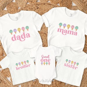 May include: A set of four white t-shirts with pink text and ice cream cone graphics. The shirts say "dada", "mama", "sweet one", and "sister".