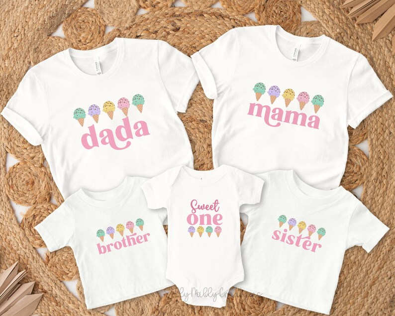 May include: A set of four white t-shirts with pink text and ice cream cone graphics. The shirts say "dada", "mama", "sweet one", and "sister".