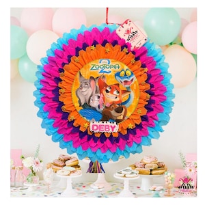 Puede incluir: Una piñata colorida y en capas con una imagen central de la película de Disney "Zootopia". La piñata presenta un diseño vibrante con papel azul, rosa, naranja y morado. El nombre "Deby" se muestra en la parte delantera.