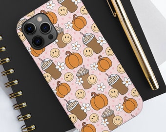 May include: A pink phone case with a pattern of smiling faces, pumpkins, and iced coffee cups.