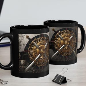 May include: Two black ceramic mugs featuring a gold shield and crossed swords design. The shield has a gold border and a central emblem. The background is a mix of grey and red.