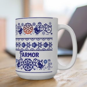 May include: White ceramic mug with a blue and white Scandinavian-inspired pattern featuring birds, flowers, and snowflakes. The word "FARMOR" is written in blue on the mug.
